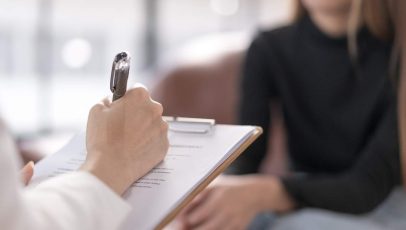 A mental health therapist taking notes during a session with a client, illustrating what different types of therapy look like in practice.